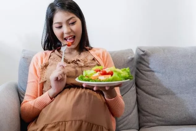 Pregnant mom holding a bowl of salad