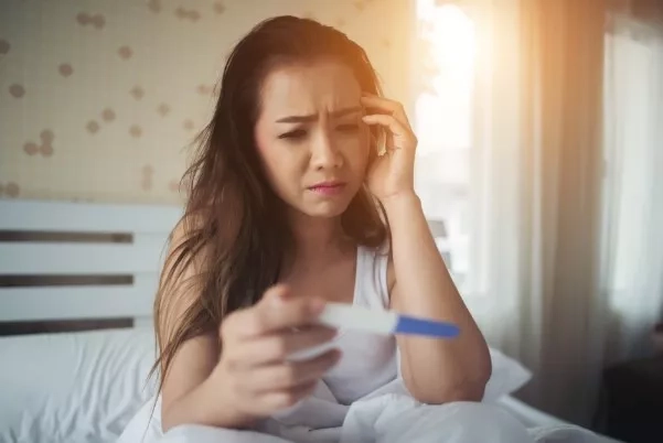 Woman holding a pregnancy kit and feeling stressed