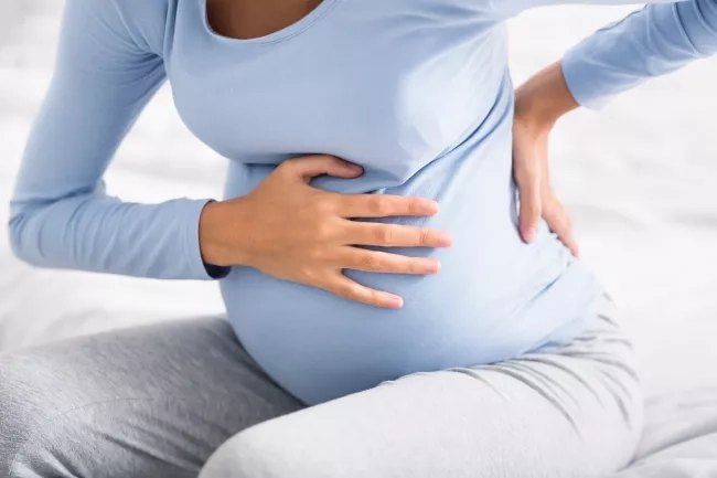 Pregnant mom holding her aching back