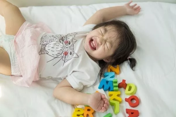 Toddler lying next to a bed alphabet letters