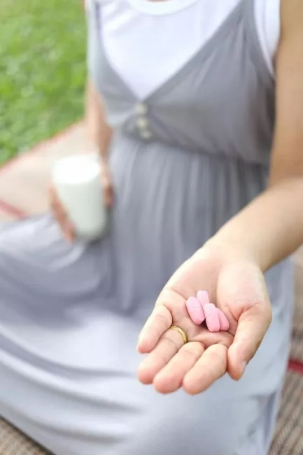 pregnant woman with vitamin pills in her palm