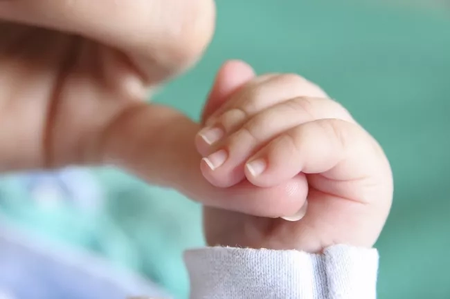 Mother holding the fingers of her baby