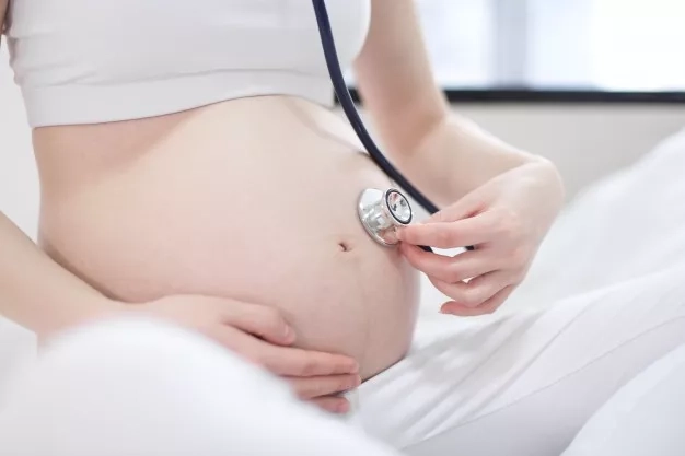 Pregnant mom holding a stethoscope to her belly