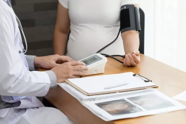 Pregnant mother getting her blood pressure checked during a doctor's visit.