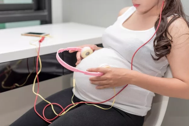 pregnant woman holding headphones to her belly