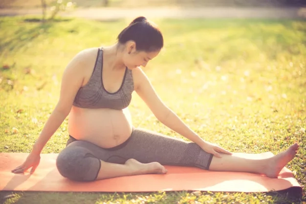 healthy pregnant woman doing yoga in nature outdoors
