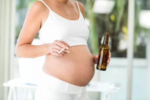 Pregnant mom holding cigarette and alcohol