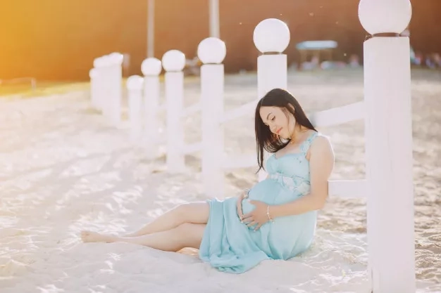 pregnant woman resting on a sandy beach