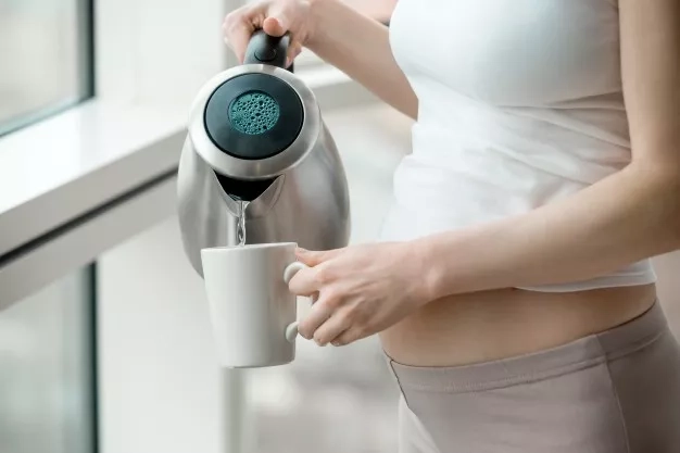 pregnant woman holding an electric kettle