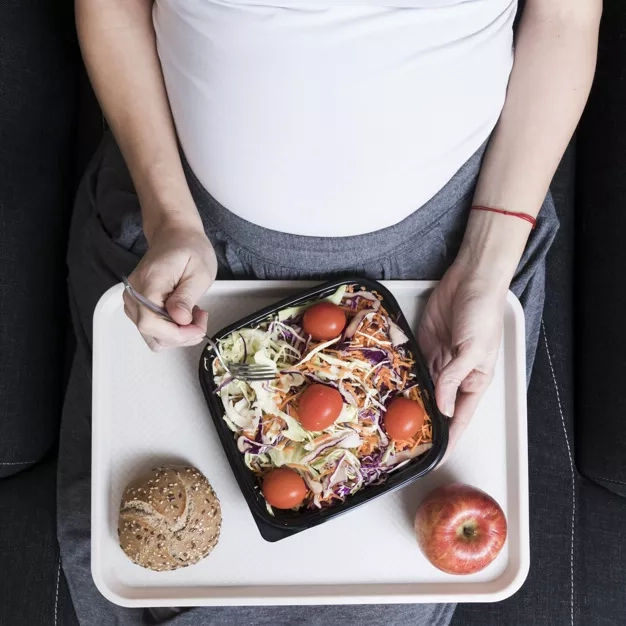 top view of pregnant woman with salad