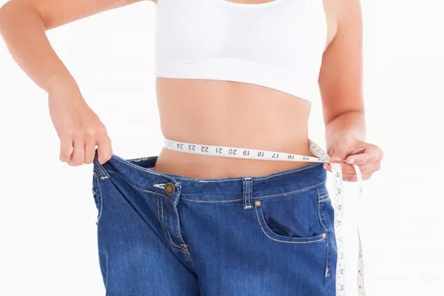 woman-measuring-her-waist-while-wearing-too-big-jeans