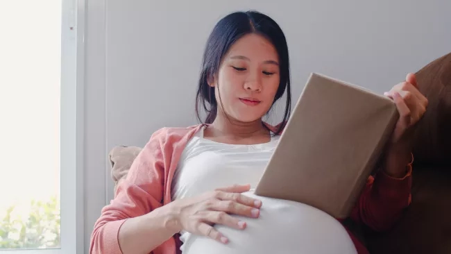 pregnant woman read a book for baby in belly